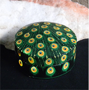 hand-painted round box with peacock feather motif.