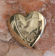 Simple gold heart brooch with hand impression on front and designer stamp on back “The Variety Club.” 