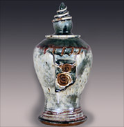 green and beige stoneware urn with spired lid