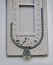 bead layout with intricate carved celedon pendant